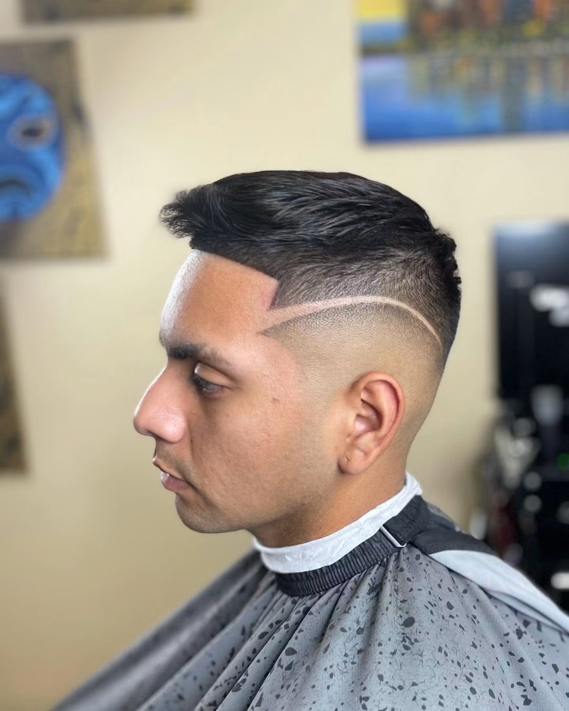 Side profile of a skin fade with a hard part and a freehand razor line through the side.