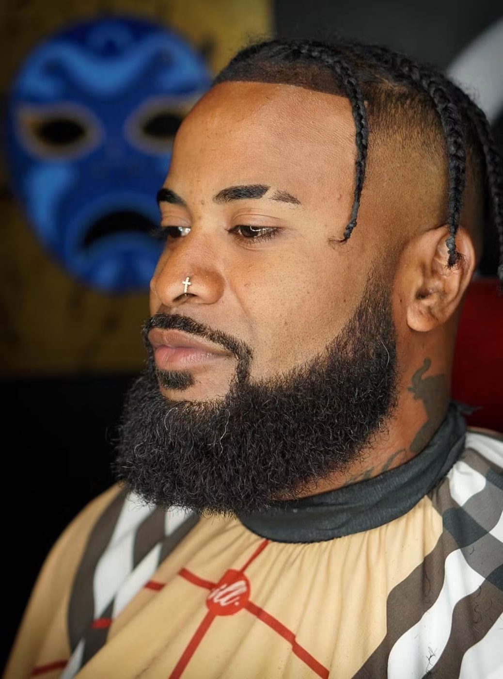 Braids with a faded side and a fully shaped, sharply lined beard.