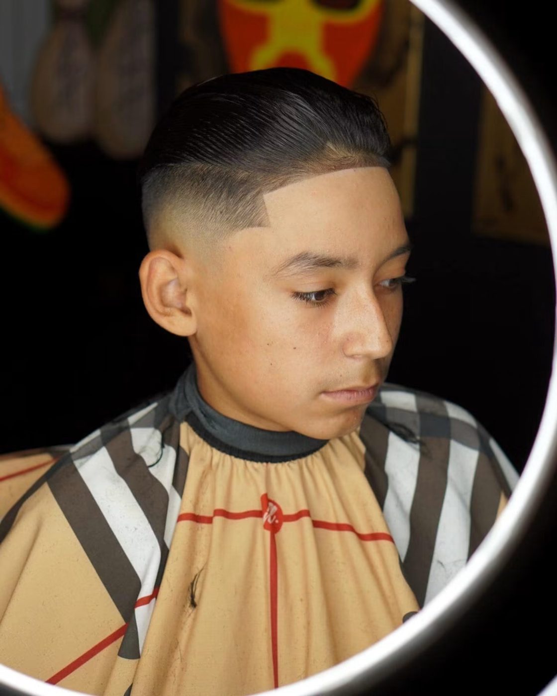 Comb-over taper with a squared line-up, lit by a ring light.