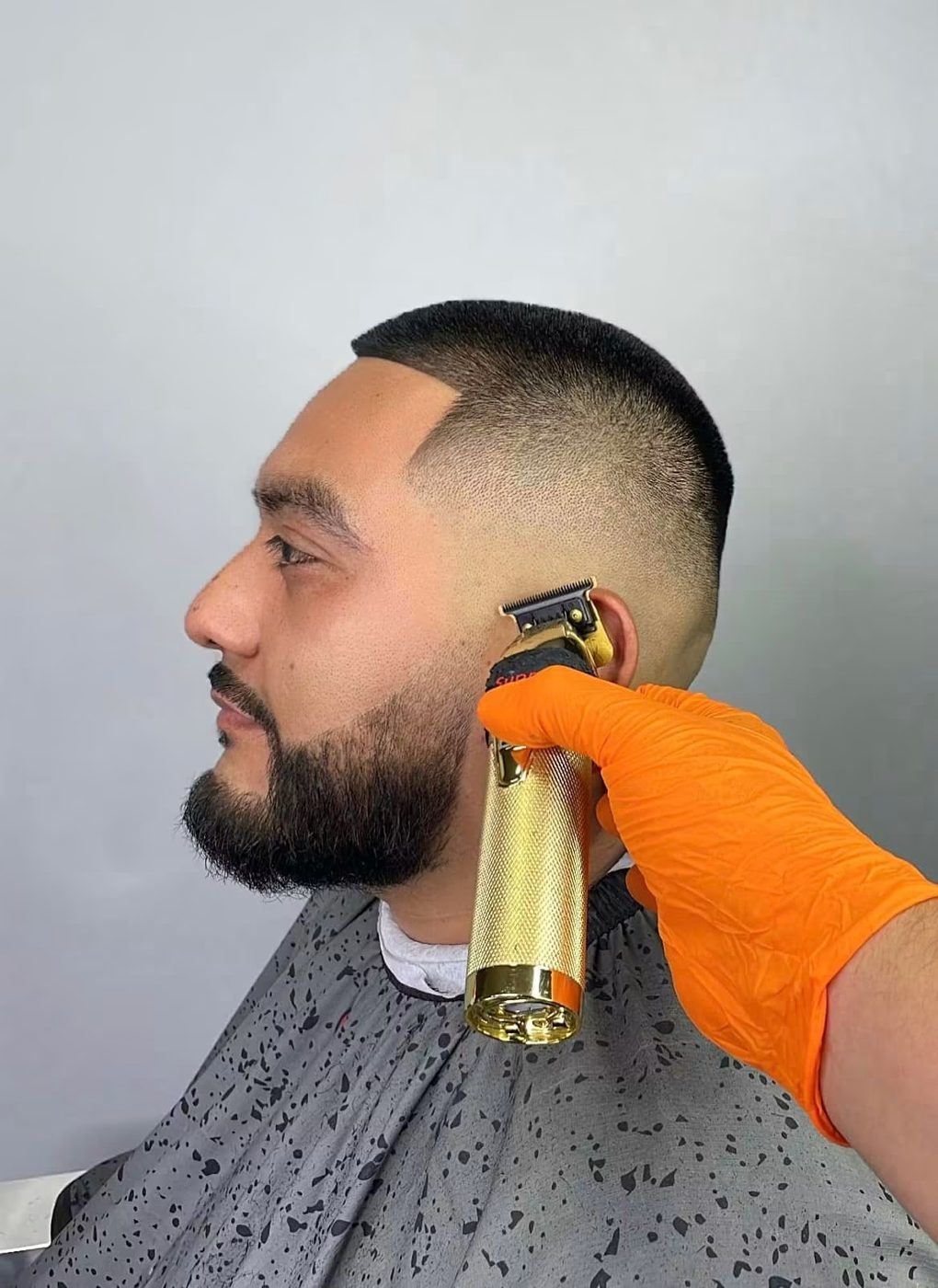 Beard line-up in progress with trimmers against a clean buzz fade.