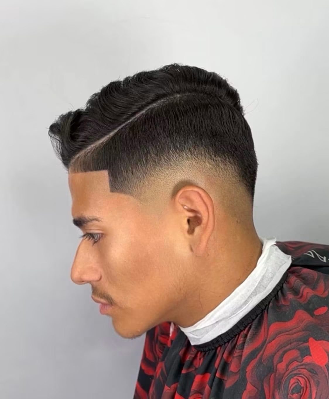 Side profile of a textured comb-over over a low taper.